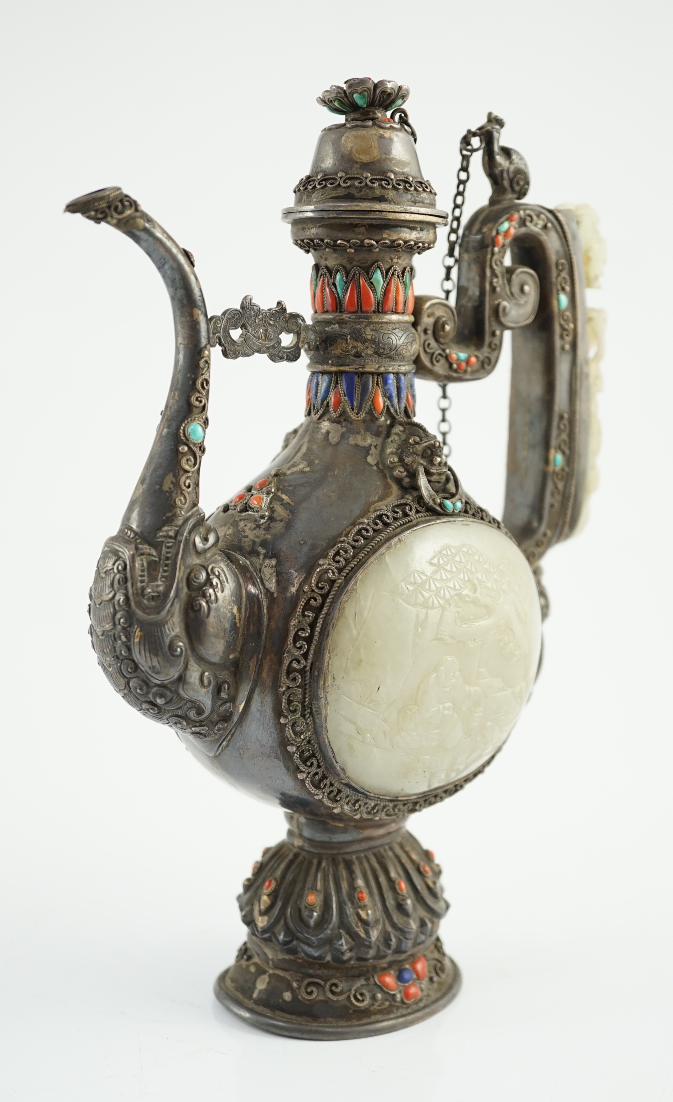 A Tibetan silver, jade, coral and hardstone mounted ewer, late 19th century, the Chinese pale celadon jades, 18th/19th century finial lacking stones